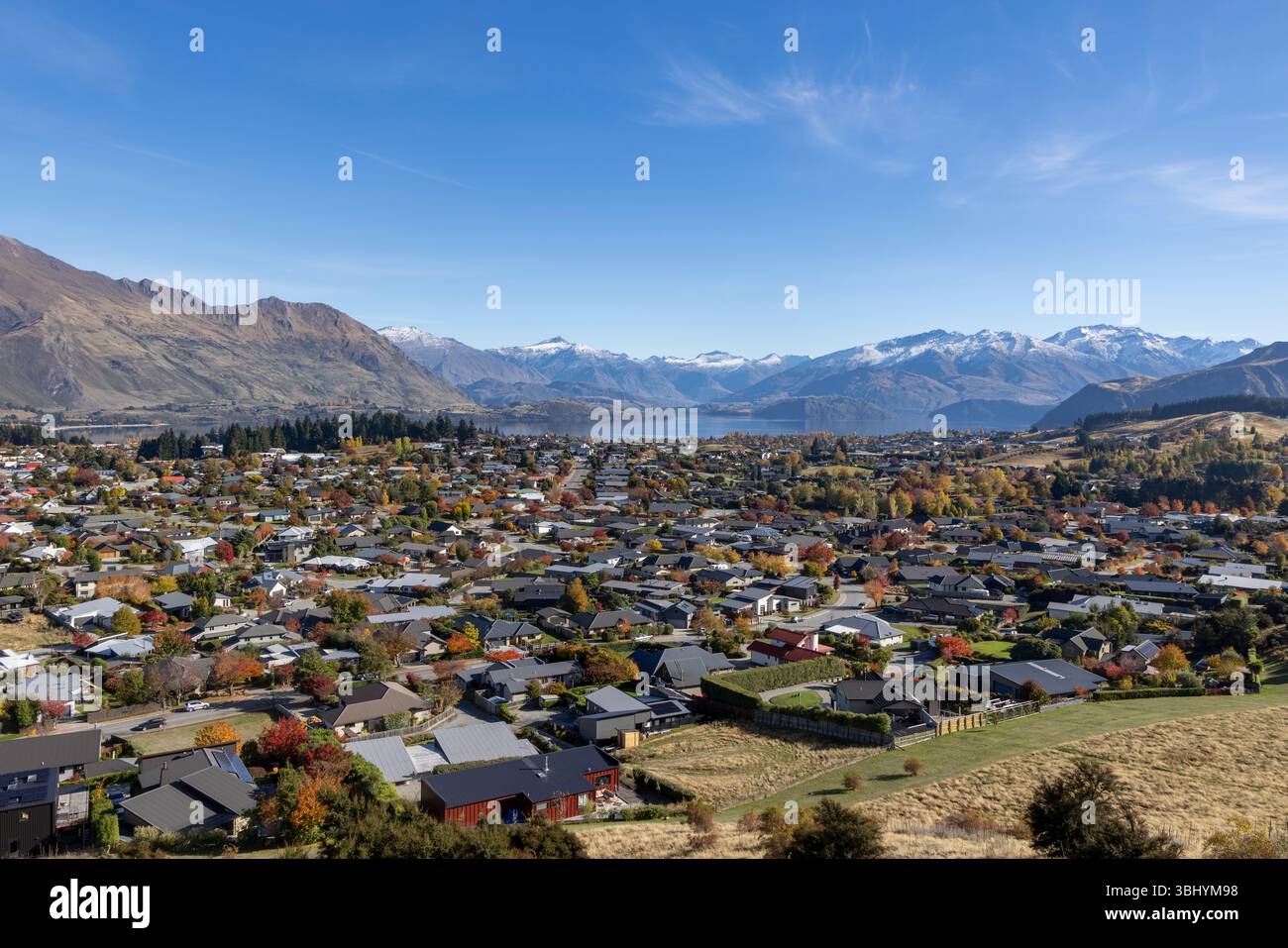 Wanaka, Otago, nuova Zelanda, vista dalla riserva ricreativa Mount Iron della città di Wanaka e delle case con il lago Wanaka e le montagne innevate del Monte aspiranti Foto Stock