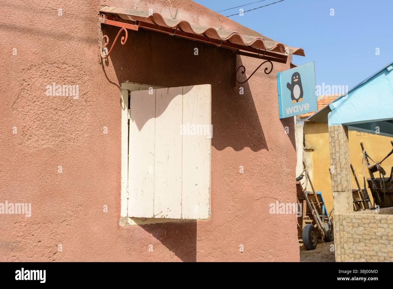 Logo dei pinguini su un cartello di denaro mobile Wave in un edificio di Joal-Fadioth (Joal-Fadiot), Petite Cote, Mbour, regione di Thies, Senegal, Africa occidentale Foto Stock