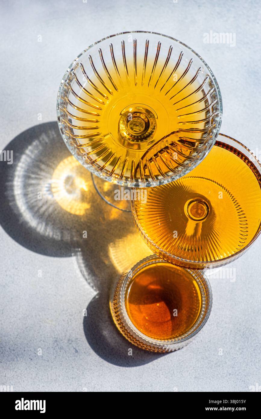 Eleganti bicchieri di cristallo pieni di vino d'ambra georgiano, che mostrano la sua ricca tonalità e il suo complesso design in vetro. La luce del sole esalta l'allettante tonnellata dorata Foto Stock