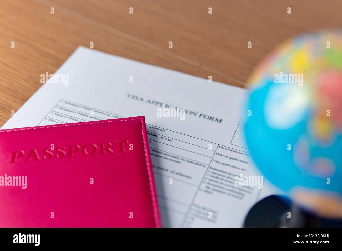 Un modulo di richiesta del visto, un passaporto rosso e un globo. Concetto di viaggio internazionale. Foto Stock
