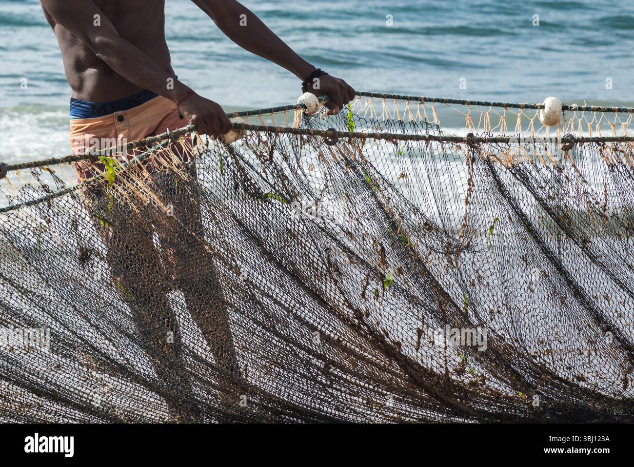 Mezzo corpo di un pescatore non identificato che tira una rete da pesca. specialità di pesce, hobby. Brasile Foto Stock