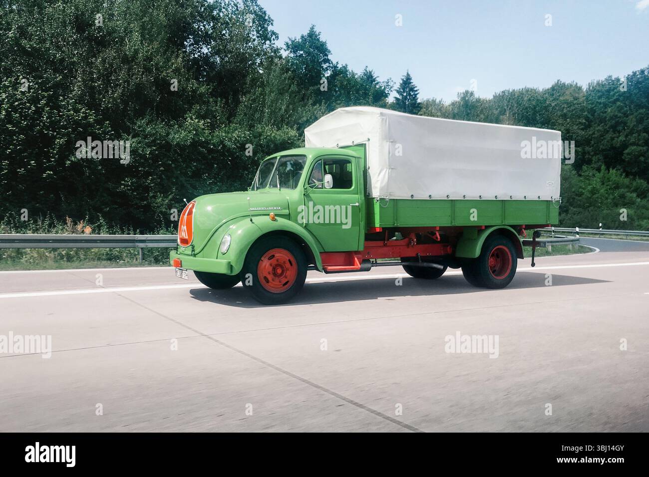 Un vecchio camion verde che guida su un'autostrada in una giornata di sole. Vista laterale del classico veicolo Magirus-Deutz Sirius Rundhauber degli anni '1960 Foto Stock