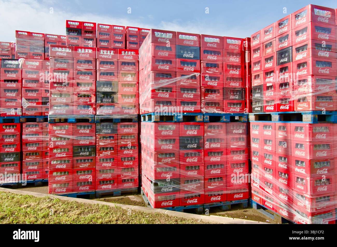 Fila di casse impilate di migliaia di bottiglie vuote di Coca-Cola su pallet pronti per essere spediti per il riciclaggio Poligono de Raos Santander Cantabria Spagna Foto Stock