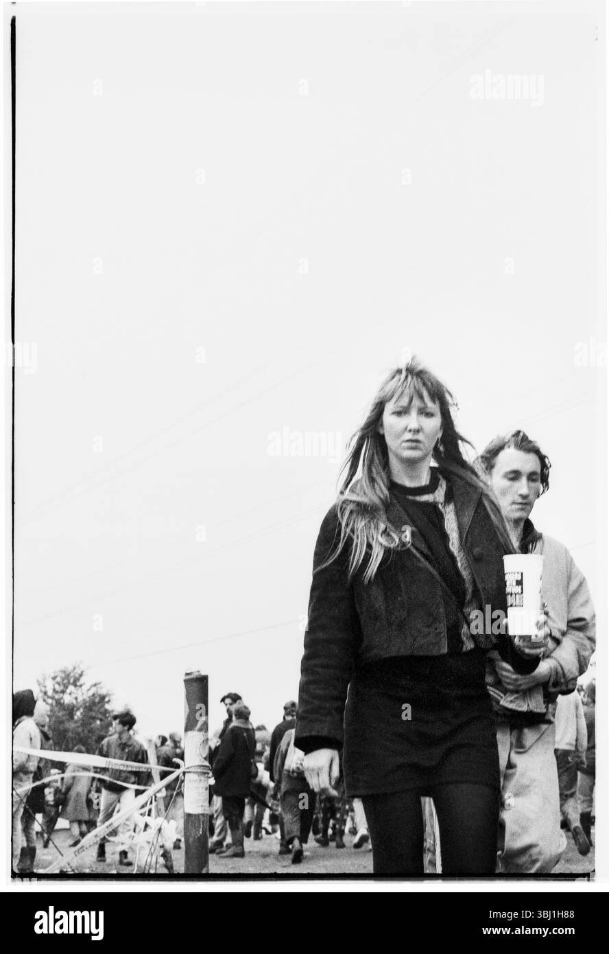 APPASSIONATI DI FESTIVAL, APPASSIONATI DI ROCK, GLASTONBURY 90: Persone in stili e mode anni '80 vagano attraverso il luogo del festival con birre in abiti caldi dopo una tempesta estiva al Glastonbury Festival, Pilton, Inghilterra, 23 giugno 1990. Fotografia: ROB WATKINS. Foto Stock