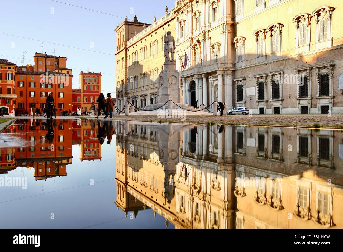 Riflesso dello storico Palazzo Ducale di Modena e della statua di Ciro Menotti in Piazza Roma coperta dall'acqua, catturando la grandezza dell'Italia Foto Stock