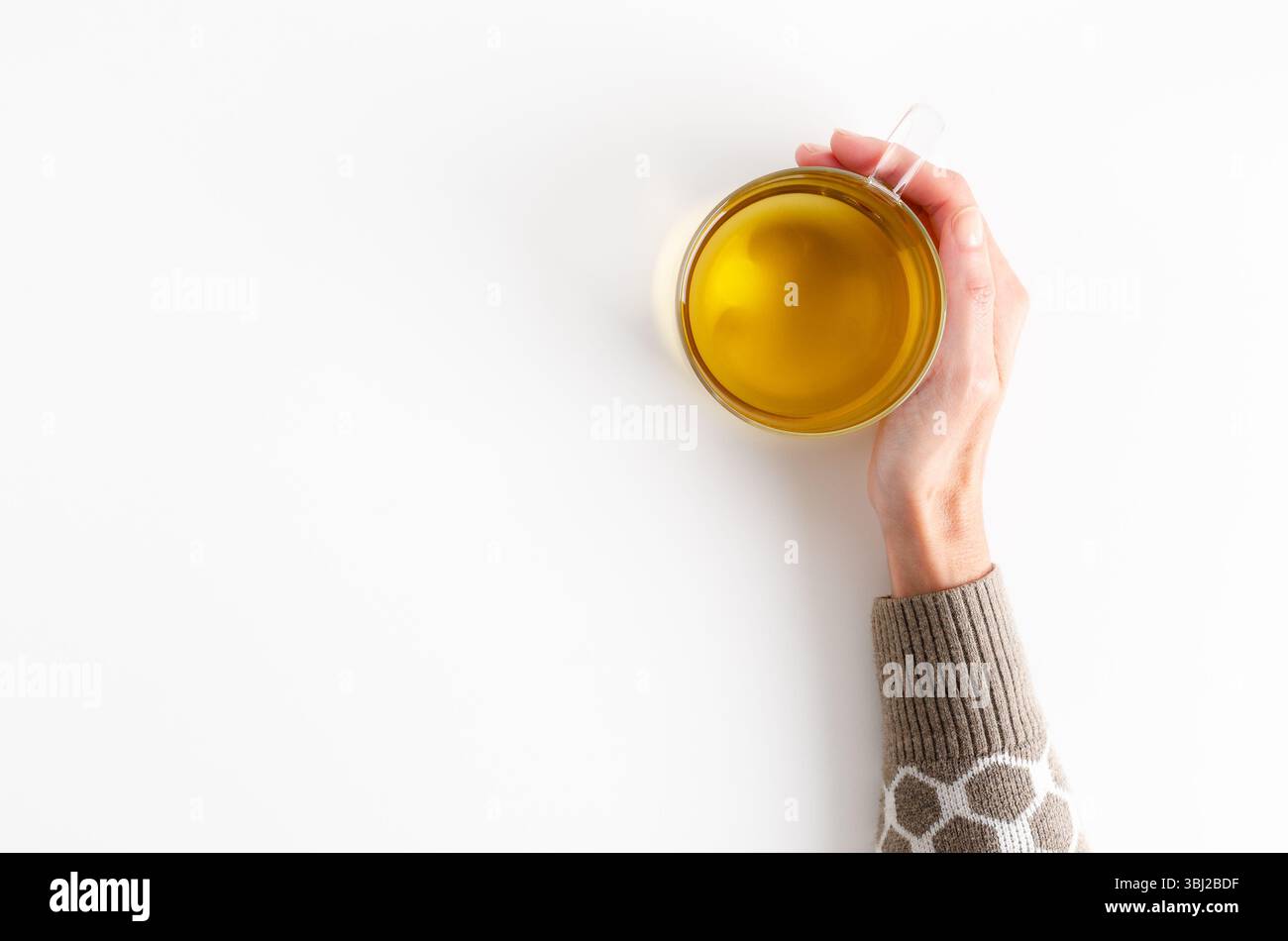 Una mano femminile che regge una tazza di tè su sfondo bianco con spazio per le copie. Foto Stock