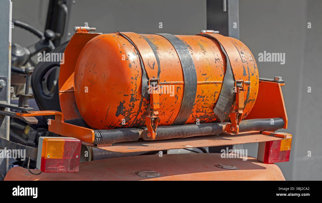 Bottiglia di GPL arancione montata sull'estremità posteriore del carrello elevatore a forche alimentato a gas Foto Stock