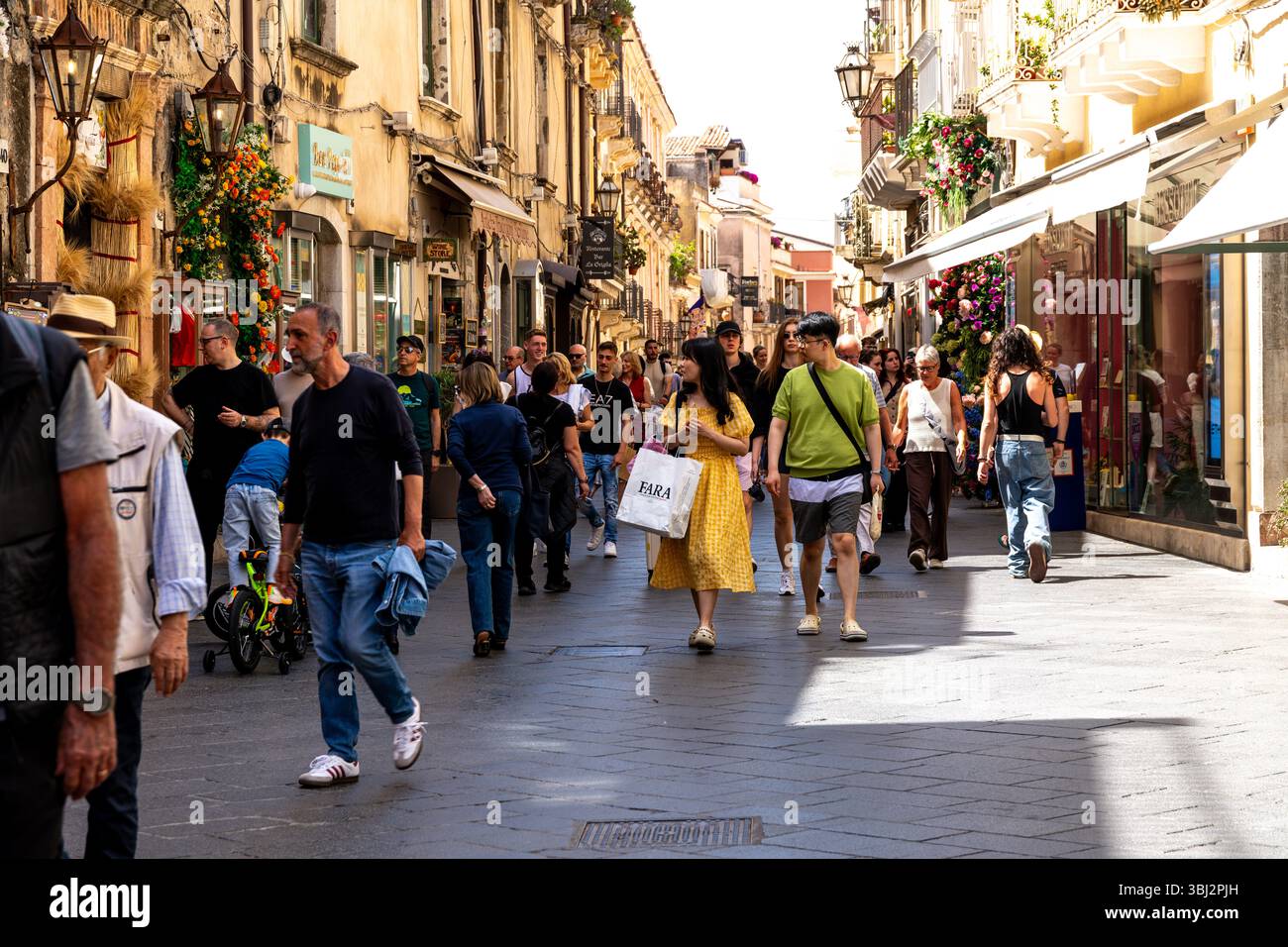 Taormina, Sizilien - Italia - 05-04-2025: Folle di persone camminano attraverso una vivace strada pedonale per lo shopping a Taormina, in Sicilia, circondata dal centro storico Foto Stock