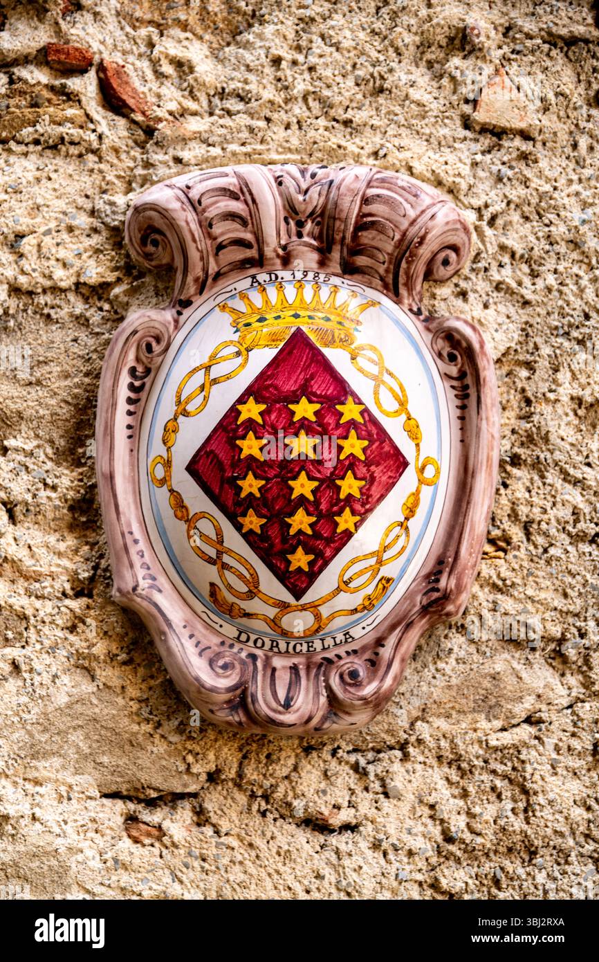 Graniti, Sizilien - Italia - 05-05-2025: Stemma in ceramica con un motivo a corona, stelle e nastro etichettato Doricella, montato su una pietra testurizzata wa Foto Stock