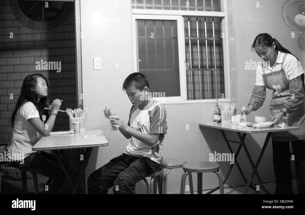 Fine degli anni '2000 Hangzhou Zhejiang Mother Tidying Family Eatery, Children snack, Black-and-White Documentary Photo Foto Stock