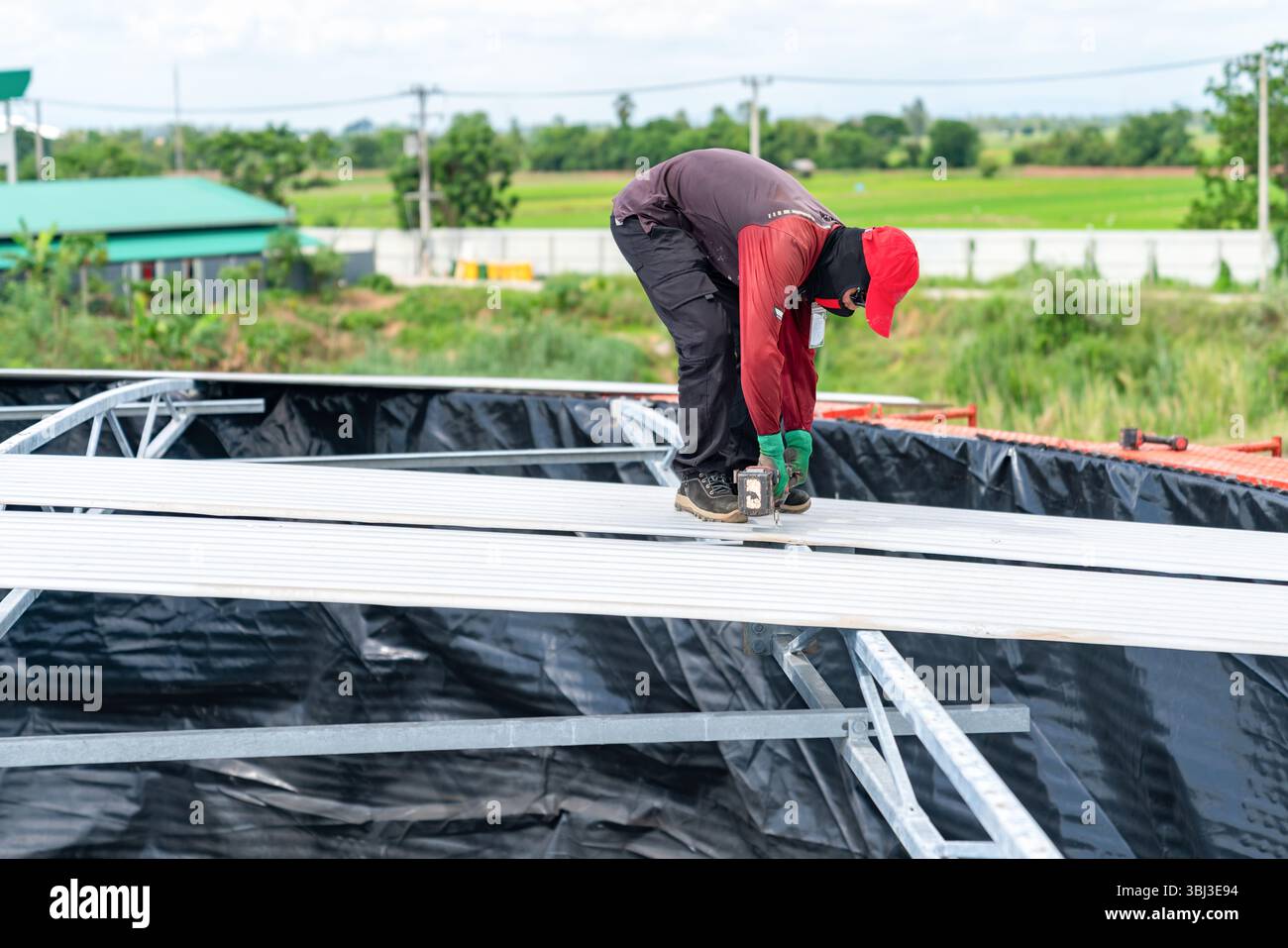 I lavoratori utilizzano cacciaviti a batteria per smontare le viti che fissano il tetto in lamiera del silo. Foto Stock