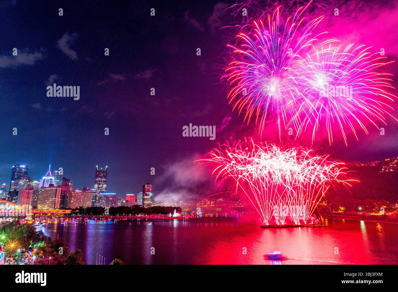 Fuochi d'artificio rosa e viola esplodono sul fiume Ohio al Point State Park di Pittsburgh durante una celebrazione del 4 luglio con vista sullo skyline della città. Foto Stock