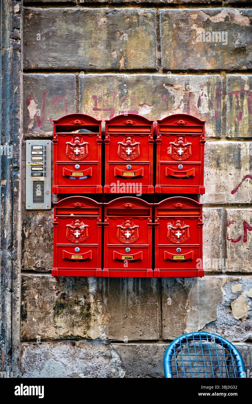 Sei caselle postali italiane rosse disposte in una griglia 2x3 e montate su un muro di mattoni a Roma, Italia. Composizione verticale dal fascino artistico e grafico. Foto Stock