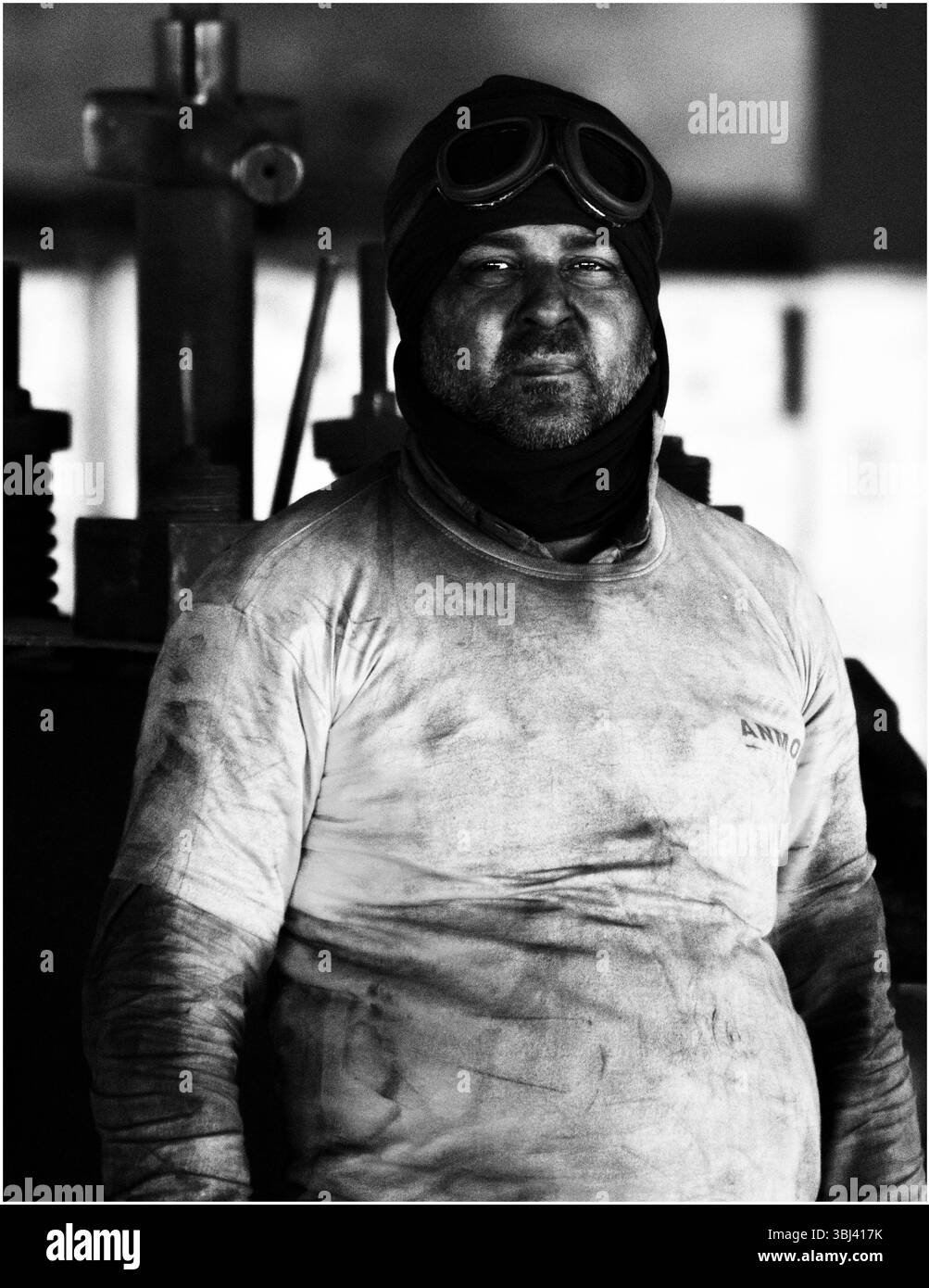 lavoratore indurito in occhiali protettivi all'interno di una fabbrica, ritratto in bianco e nero Foto Stock