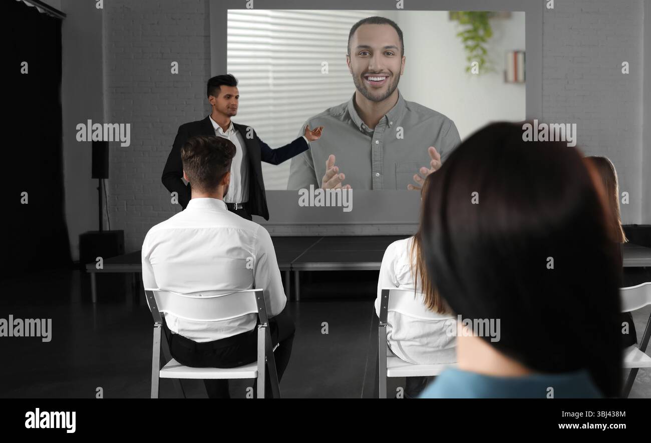 Gruppo di persone che partecipano a una conferenza aziendale al chiuso. Altoparlante sullo schermo di proiezione Foto Stock