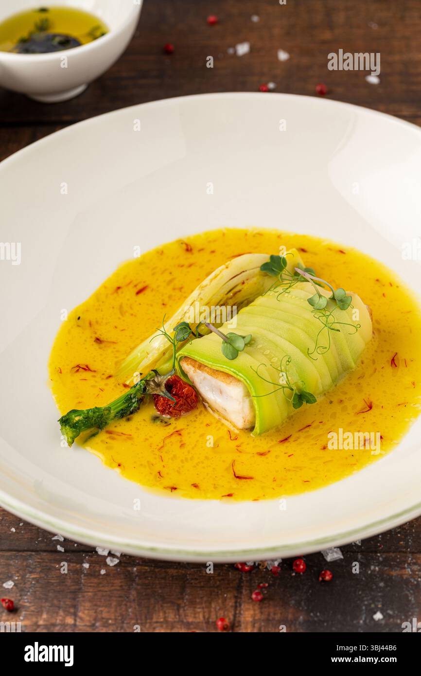 Filetto di pesce ricoperto di zucchine in salsa gialla allo zafferano Foto Stock
