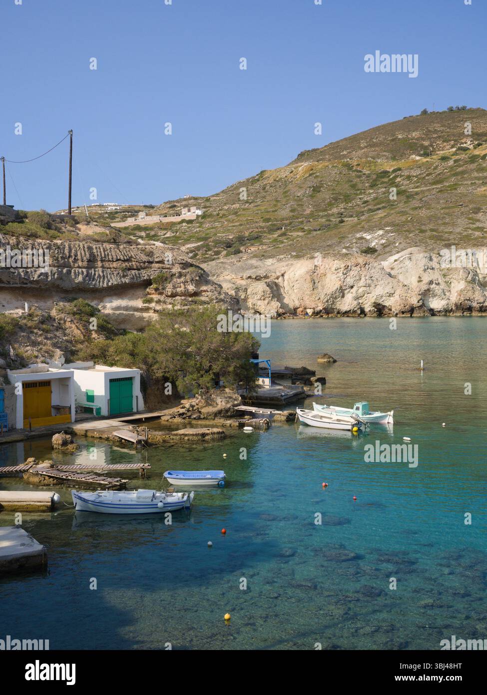 Vivaci rifugi per la pesca e scogliere rocciose a Mandrakia, Milos, Grecia. L'acqua turchese e la luce brillante catturano il fascino tranquillo di questo villaggio dell'isola. Foto Stock