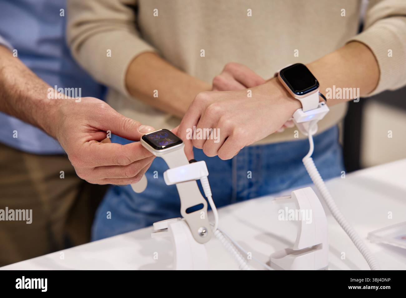 In un ambiente retail, i clienti che provano con entusiasmo una varietà di smartwatch diversi si stanno impegnando attivamente con le nuove tecnologie nel rapido sviluppo Foto Stock