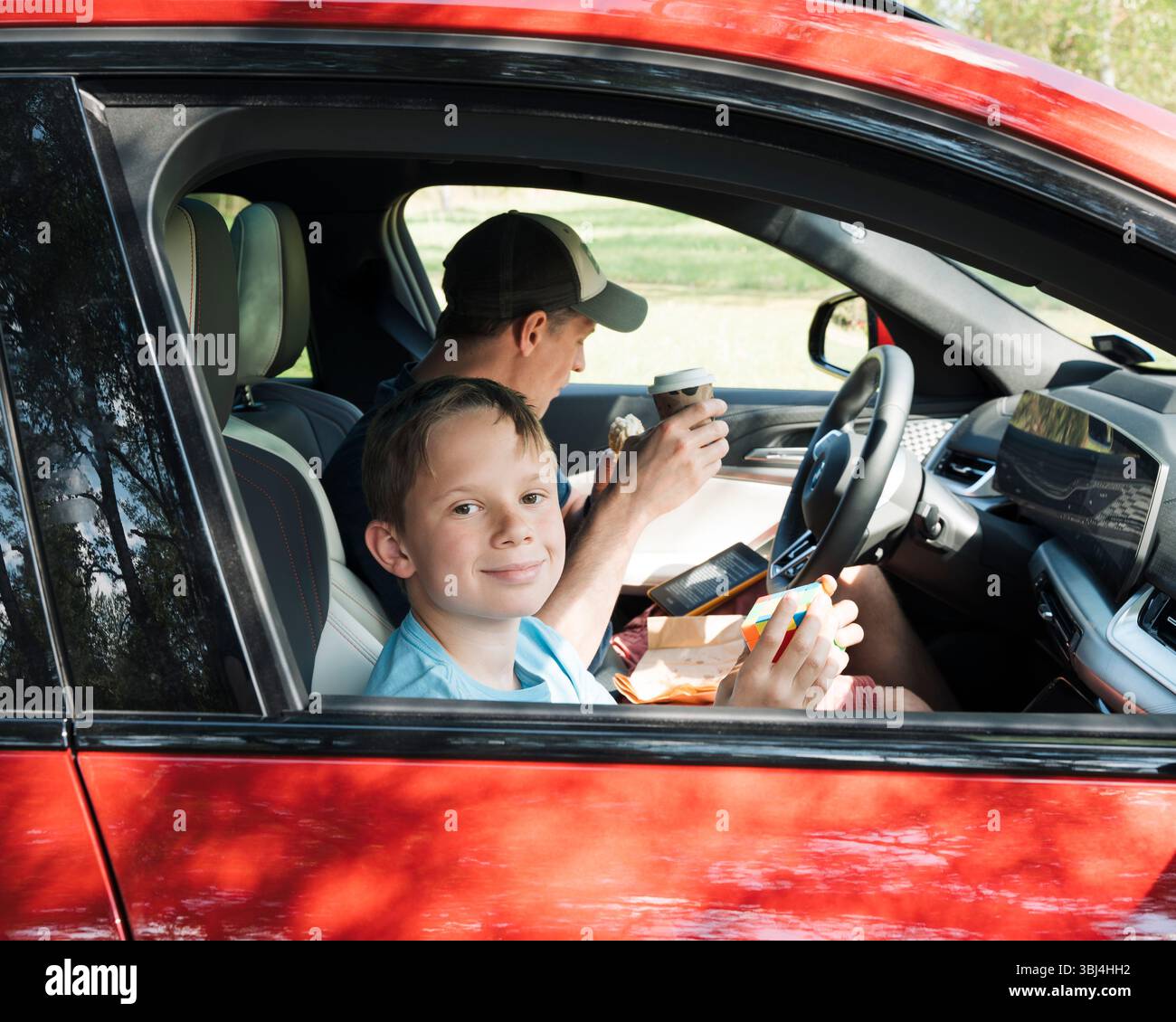 padre e figlio sedevano in macchina insieme mangiando spuntini e giocando Foto Stock