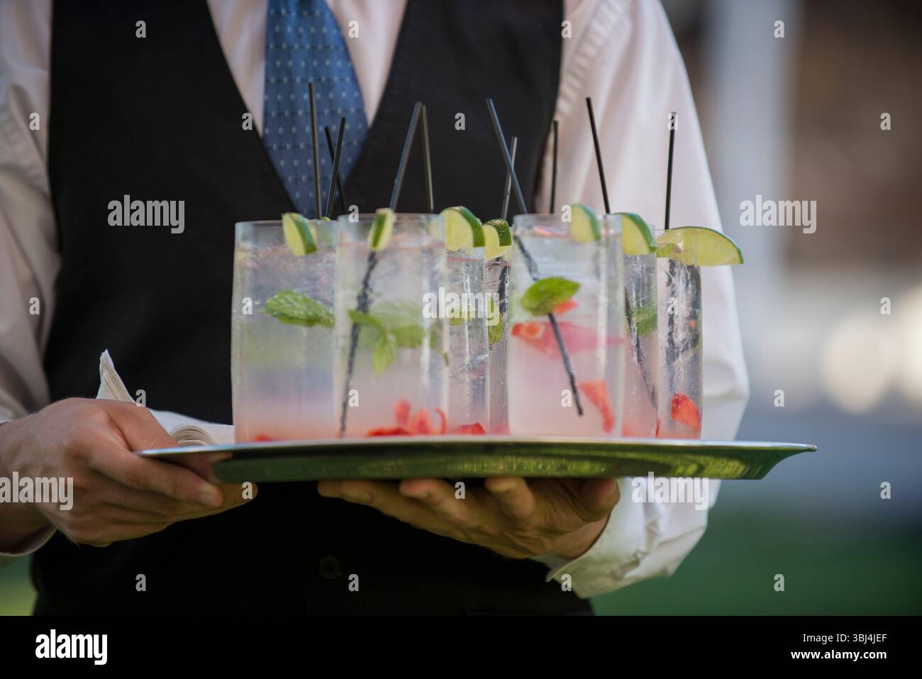 Un server che tiene un vassoio di rinfrescanti cocktail estivi Foto Stock