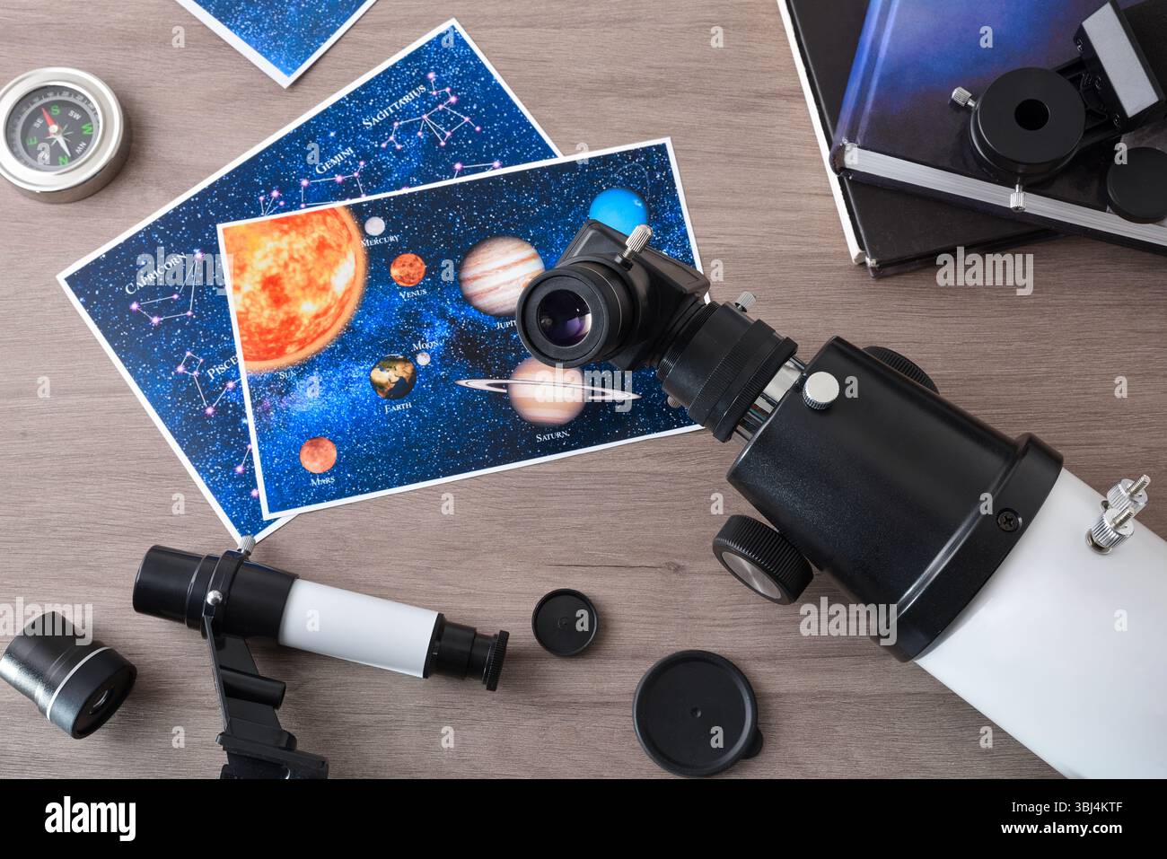 Concetto di studio astronomico con dettaglio dell'oculare di un telescopio studentesco con materiale, libri e fotografie su un tavolo di legno. Vista dall'alto. Foto Stock