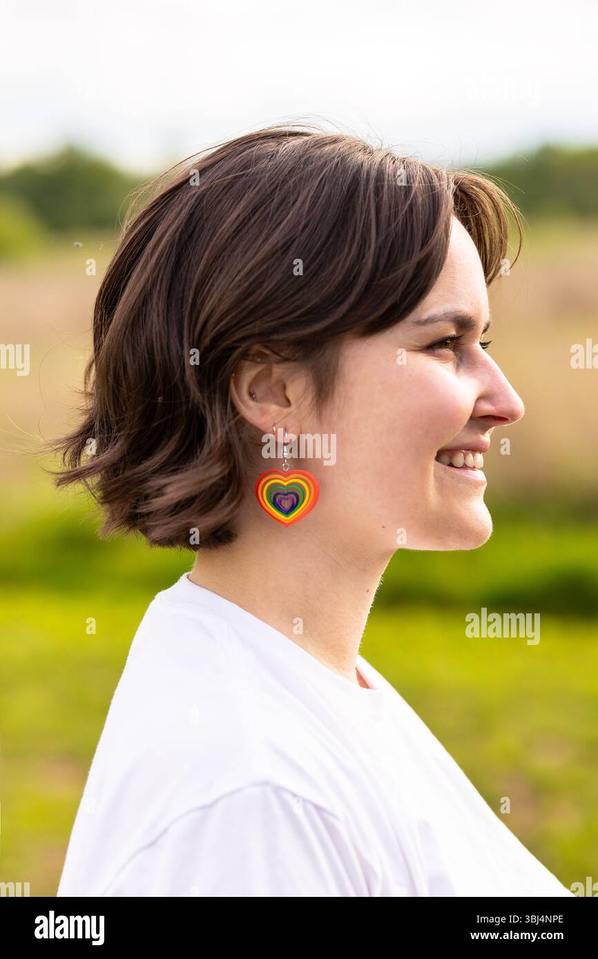 primo piano di una giovane donna che indossa orecchini a cuore arcobaleno Foto Stock