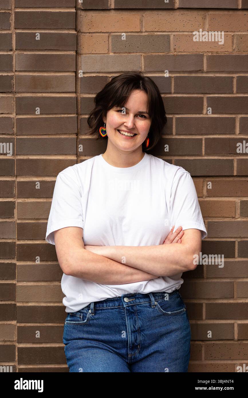 ritratto di una donna che indossa una t-shirt bianca e orecchini arcobaleno Foto Stock