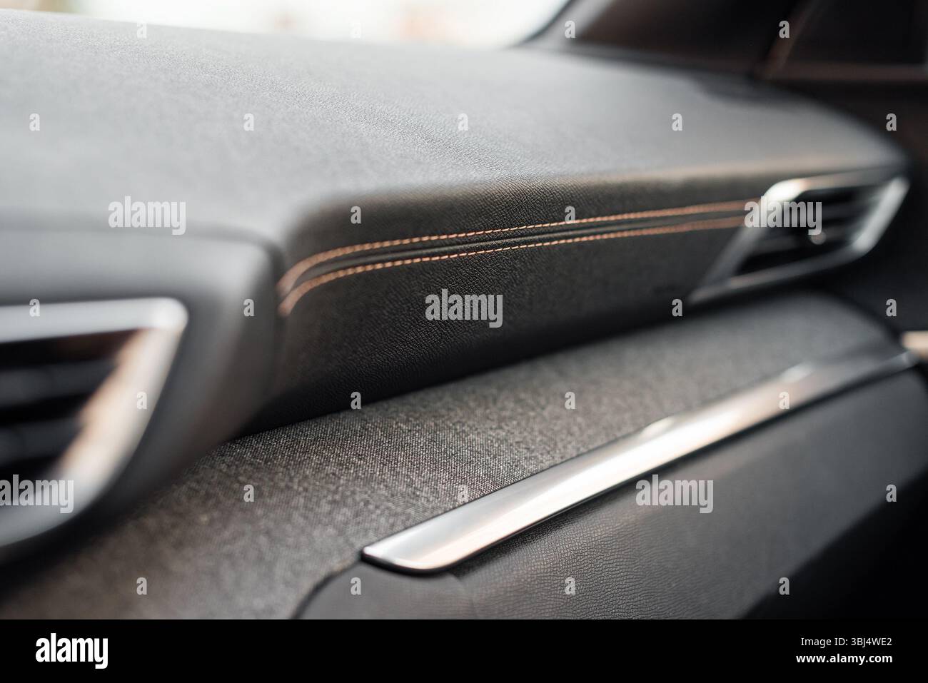 Pannello anteriore rivestito in pelle in un'auto. Interni della nuova automobile con cuciture in bronzo e rivestimento in tessuto grigio. Foto Stock