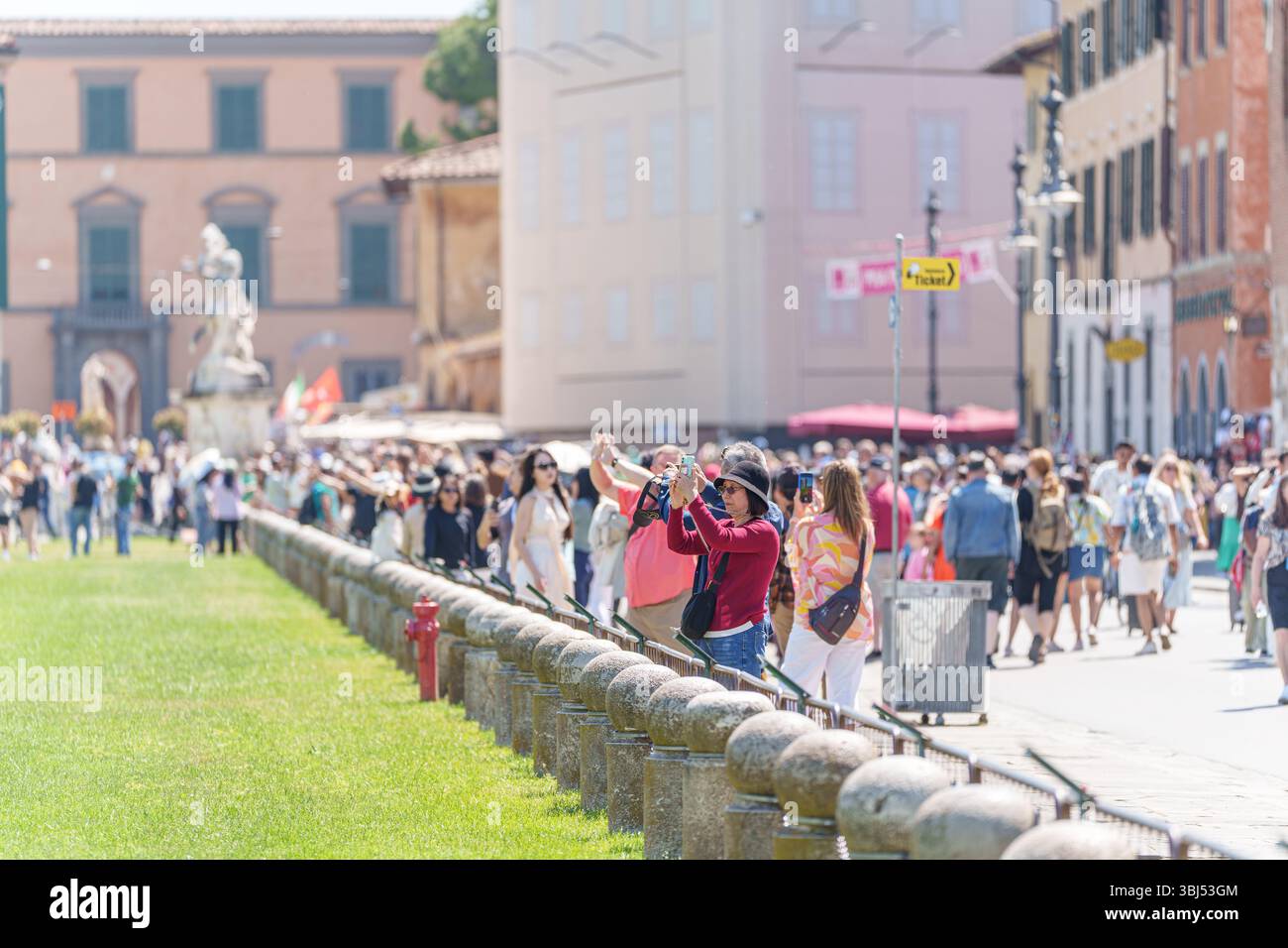 I turisti si mettono in posa con la Torre Pendente di Pisa, fingendo di trattenerla in una divertente foto di viaggio. 14 maggio 2025 Foto Stock