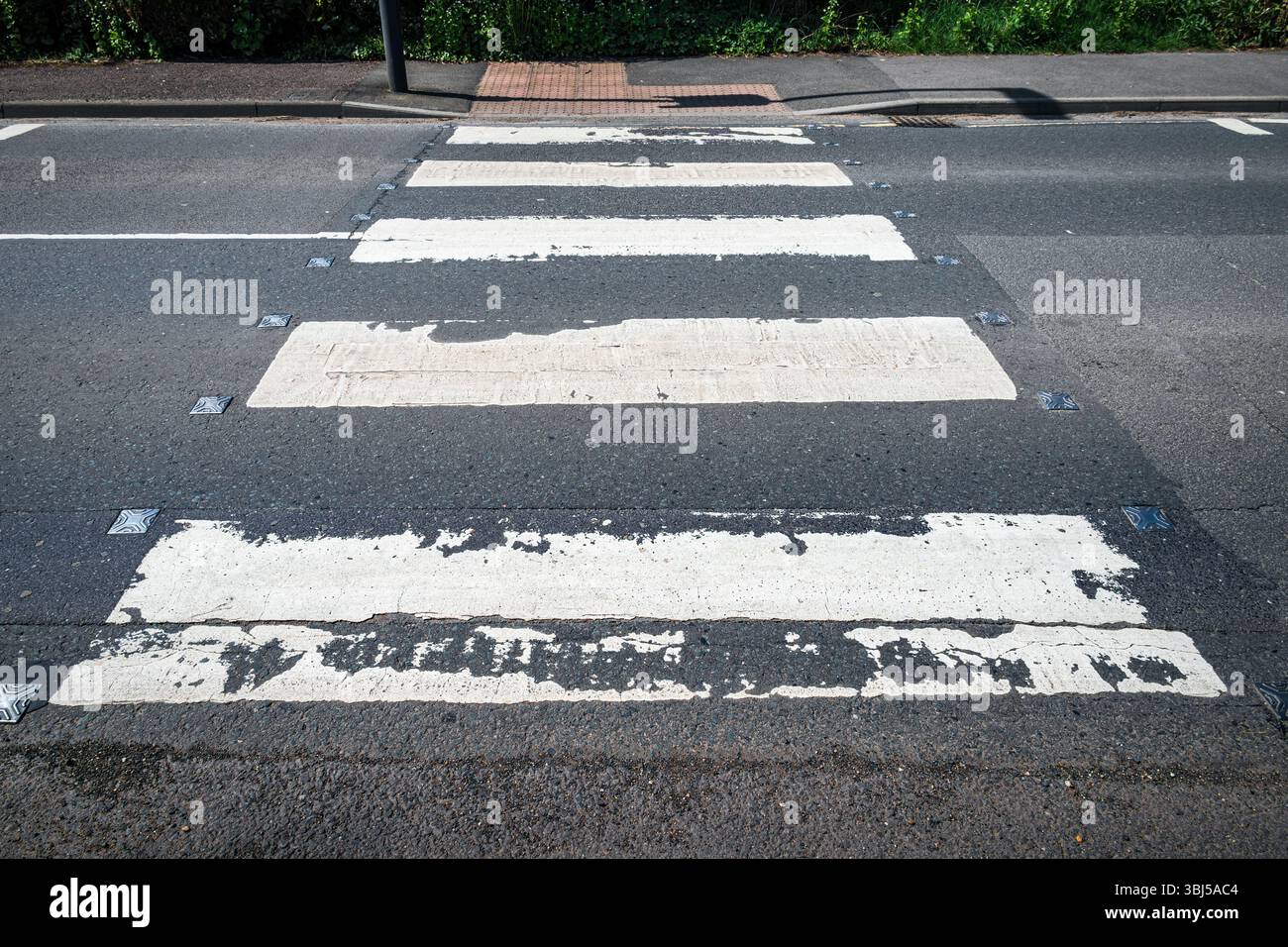 I cartelli stradali di un incrocio zebrato, alcuni bordi stropicciati dal tempo, testimoniano infiniti attraversamenti Foto Stock