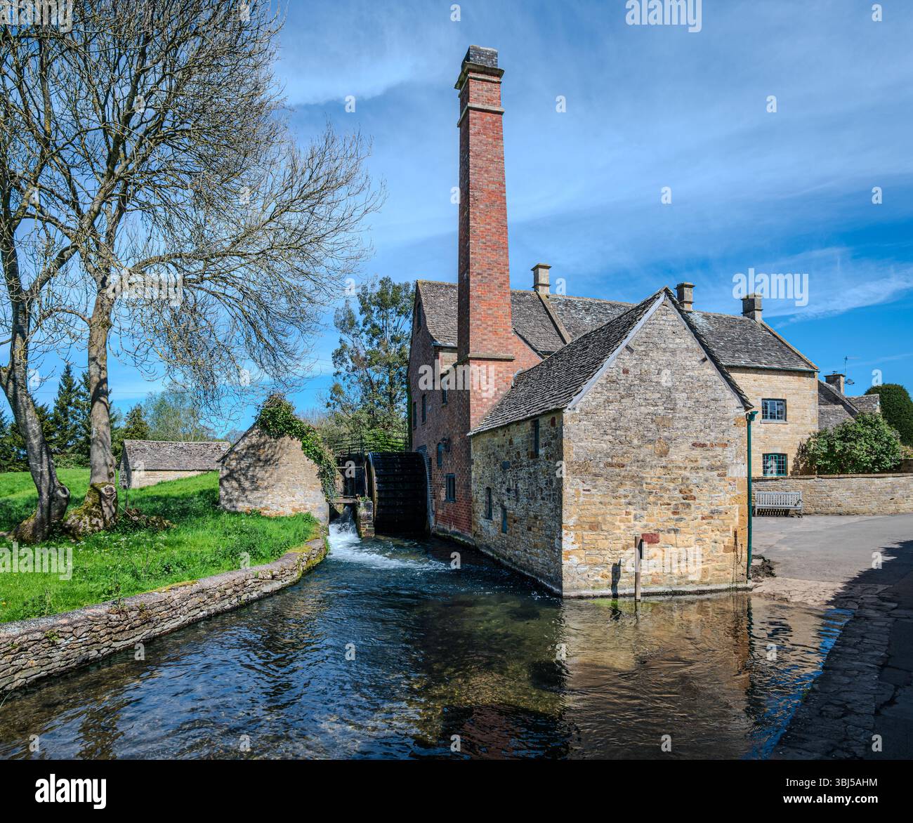 L'Old Mill in Lower Slaughter si erge come una reliquia conservata del passato industriale del villaggio, che funge da museo sotto un cielo primaverile limpido Foto Stock