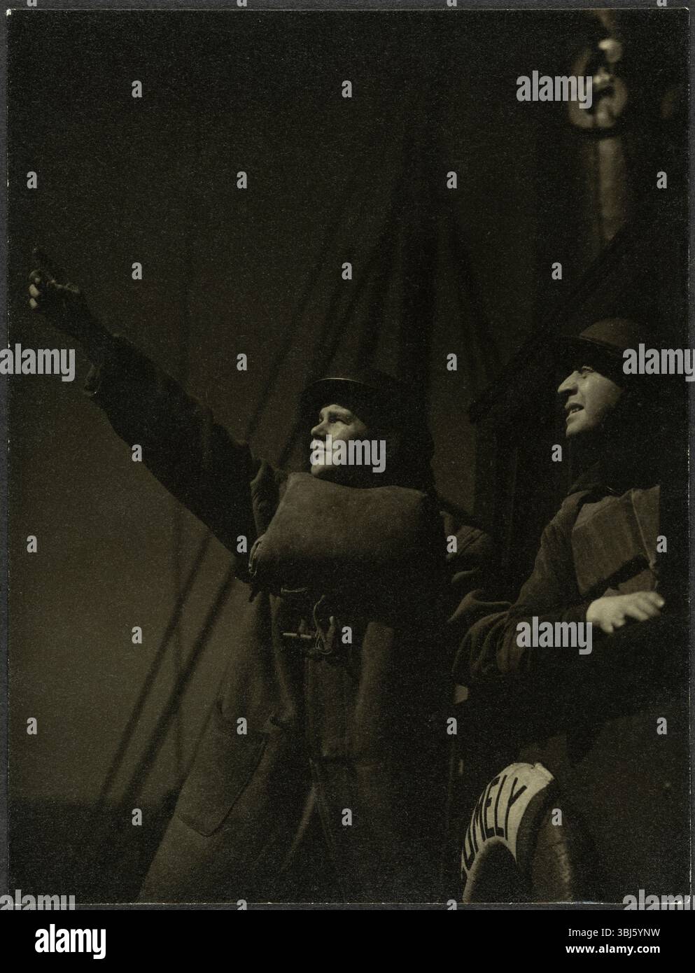 Sempre dal film Operational Height prodotto dalla RAF Film Production Unit durante la seconda guerra mondiale, mostrando due uomini in uniforme a bordo di una nave di notte, 1942. Operational Height è un film prodotto dalla Royal Air Force Film Production Unit durante la seconda guerra mondiale. "Ha dato un resoconto drammatico del lavoro dei palloni da sbarramento della RAF volati in mare nell'estuario del Tamigi". Il film è stato digitalizzato e può essere visualizzato sul sito web Imperial War Museum Collections. Foto Stock