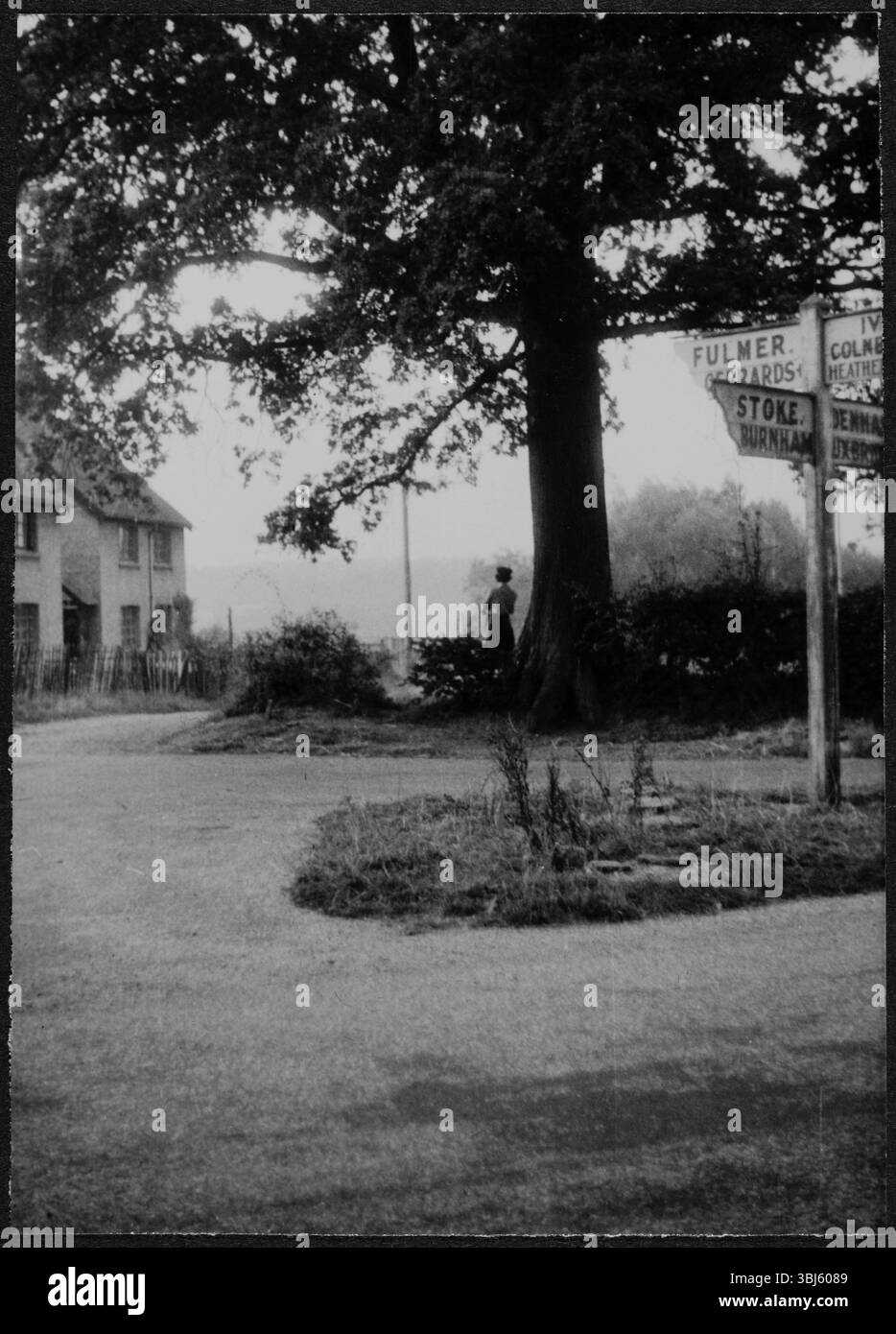 Una donna in uniforme WAAF, in piedi sotto un albero, vicino a un cartello con le dita vicino a RAF Iver Heath, Pinewood Studios, Buckinghamshire, 1942-43. Pinewood Studios - o RAF Iver Heath - è stato utilizzato come base durante la seconda guerra mondiale per la Royal Air Force Film Production Unit, la Crown Film Unit e l'Army Film and Photographic Unit. Gli studi sono stati utilizzati per produrre sia film che sostenevano il ruolo delle forze armate nella guerra, sia film documentari, registrando i progressi della guerra. Dorothy 'Knicky' Chapman è stata inviata ai Pinewood Studios per servire come WAAF con la RAF's Film Production Unit, Foto Stock