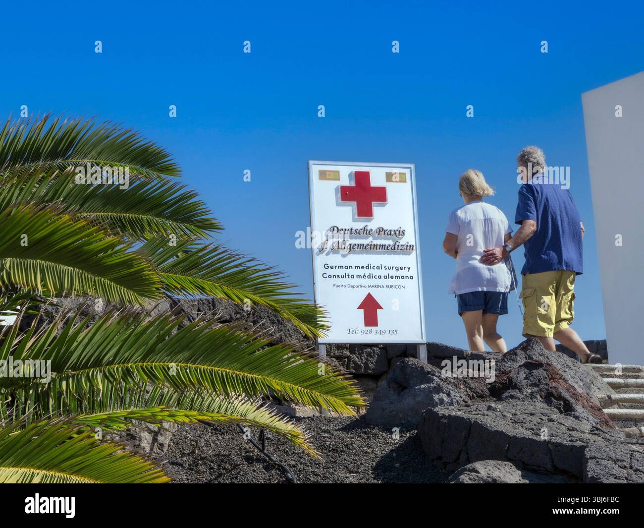 Vacanze cure mediche all'estero coppia e firmare per cure mediche locali cure cliniche in sole località di vacanza con palme e cielo blu Foto Stock