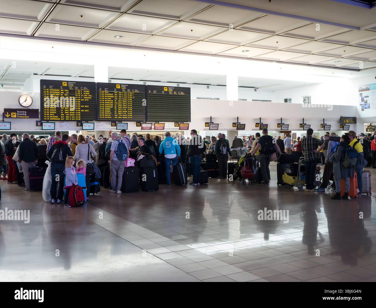 Check-in aeroportuale, coda dei passeggeri dei voli charter e bagagli aspettano al terminal dell'aeroporto per effettuare il check-in dei bagagli al volo di ritorno da Lanzarote, Spagna Foto Stock