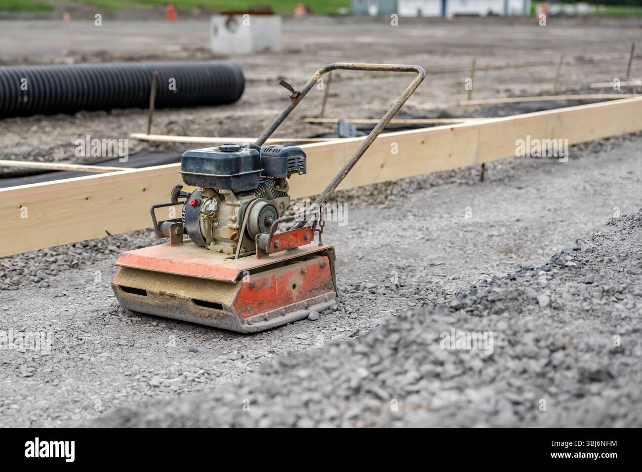 Compattatore a piastra vibrante in cantiere su superfici in pietra compattata. Foto Stock