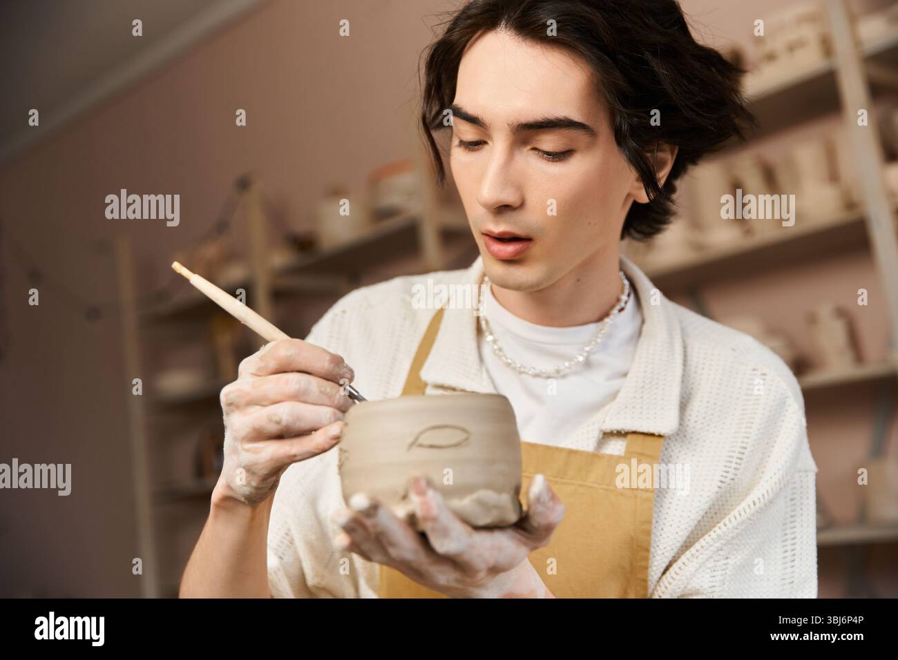 Un uomo elegante forma meticolosamente l'argilla in un luminoso studio di ceramica, mostrando il suo stile creativo. Foto Stock