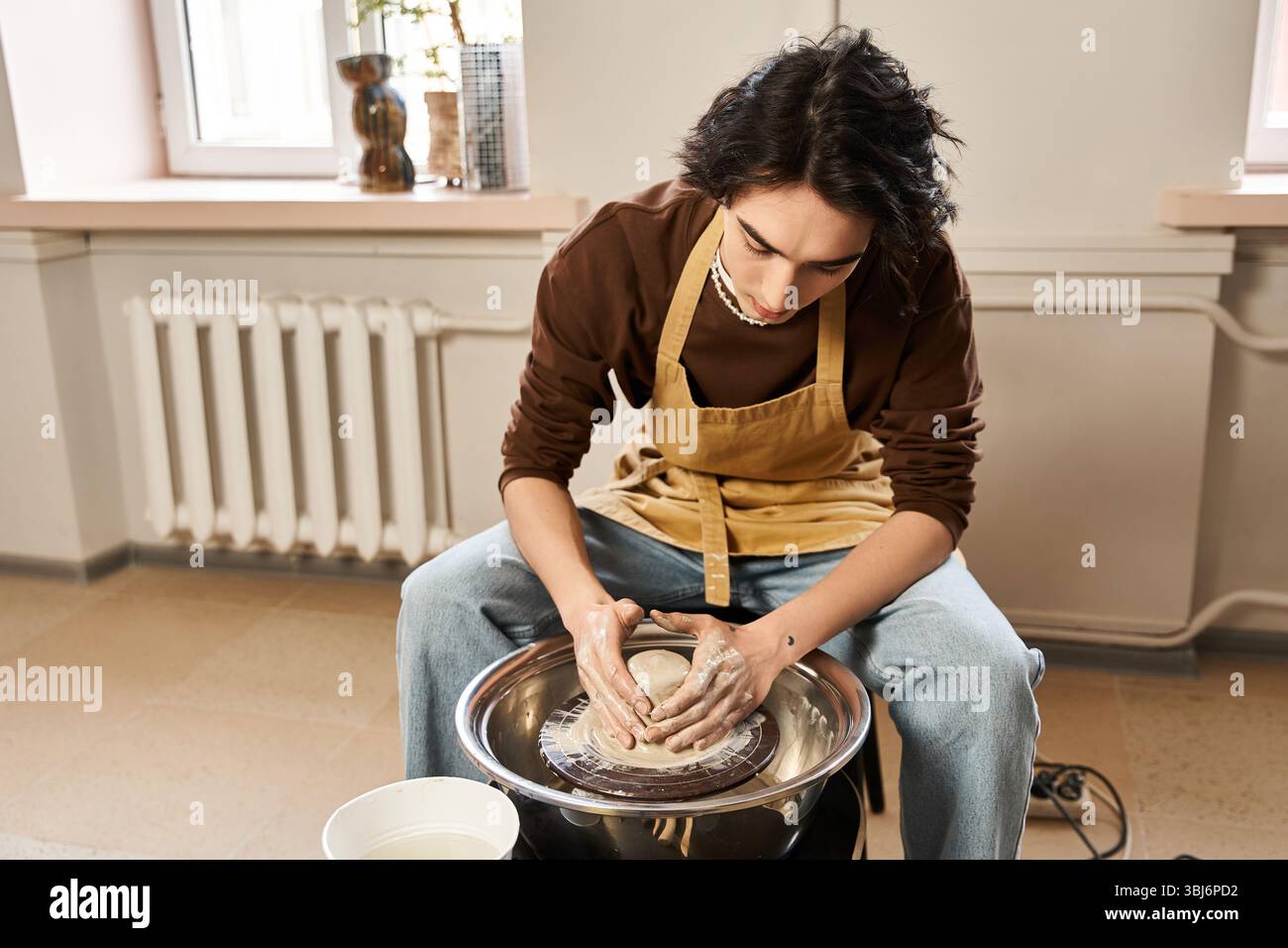 L'uomo elegante modella sapientemente l'argilla nel suo studio di ceramica, incarnando creatività e passione artistica. Foto Stock