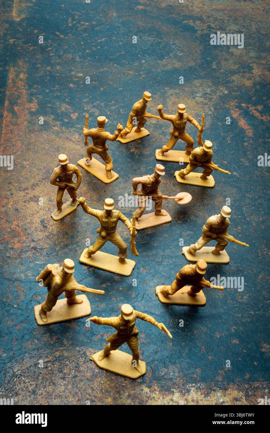I piccoli soldati di plastica giocattolo sono posizionati in modo giocoso su una superficie ruvida. Le loro pose suggeriscono movimenti e azioni Foto Stock