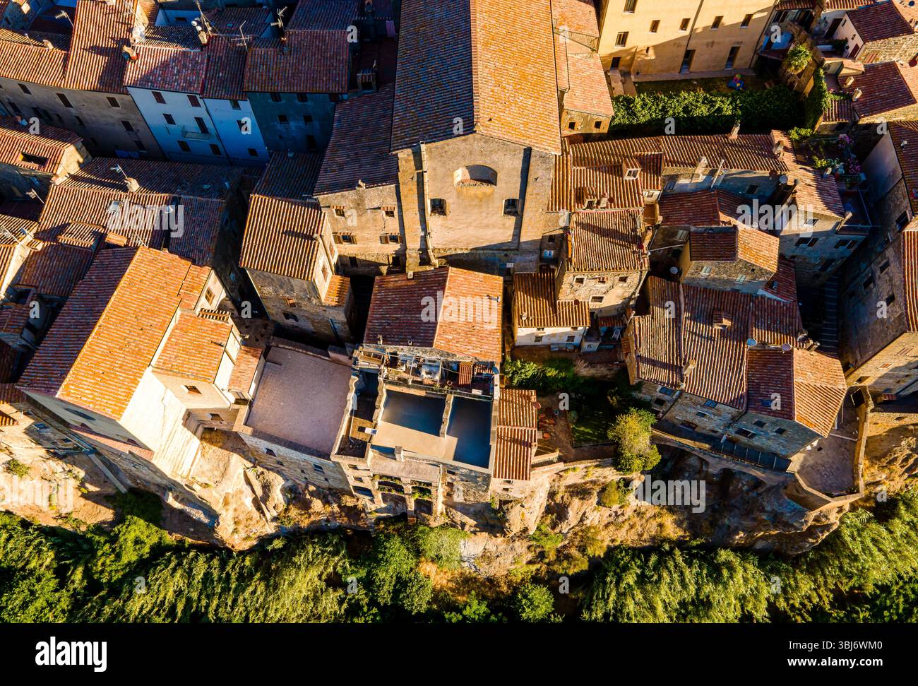 Vista aerea con droni di Pitigliano, Toscana, Italia, con caldi tetti arancioni, tonalità dorate e l'affascinante cittadina collinare nella pittoresca regione vinicola. Foto Stock