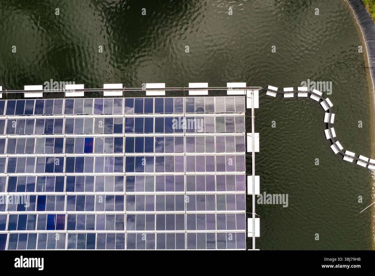 Impianto solare galleggiante con file di pannelli fotovoltaici montati sull'acqua, che produce energia elettrica rinnovabile senza inquinamento atmosferico. Concetto di eco Foto Stock