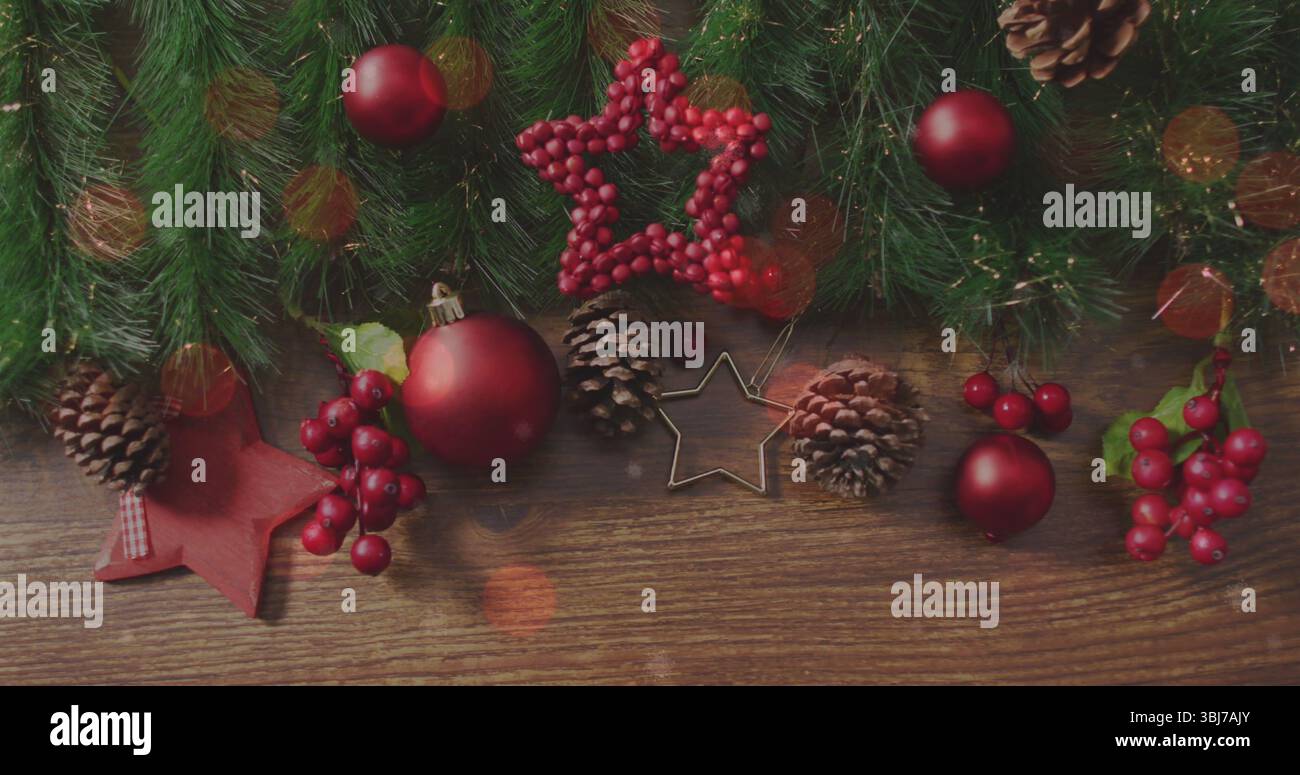 Decorazioni natalizie su un tavolo in legno con baubles rossi, rami di pino e fornelli a stella Foto Stock