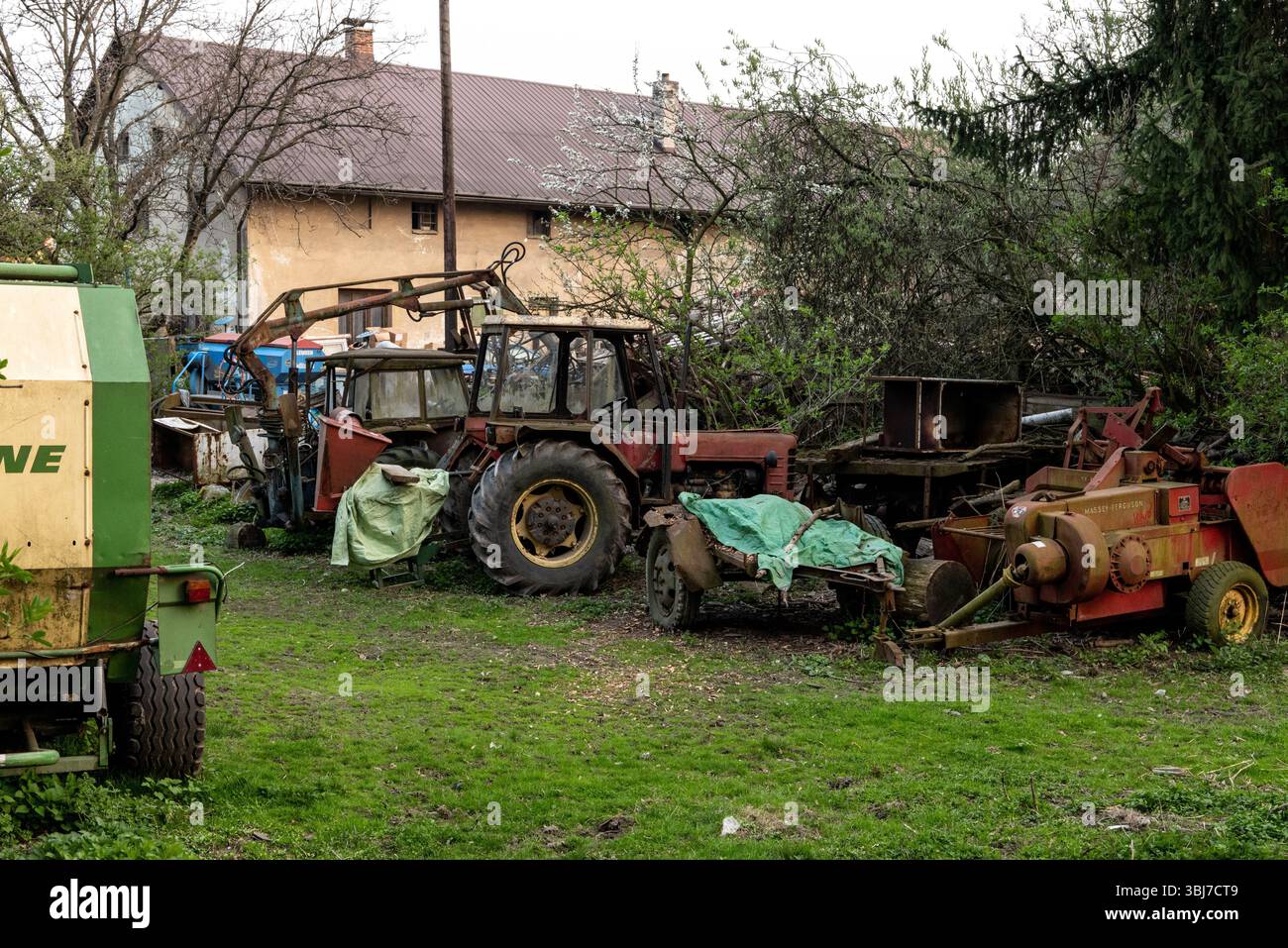 OSTRAVA, REPUBBLICA CECA - 9 APRILE 2019: Trattore rosso ceco molto vecchio con una grande ruota posteriore e molte attrezzature abbandonate in un campo Foto Stock