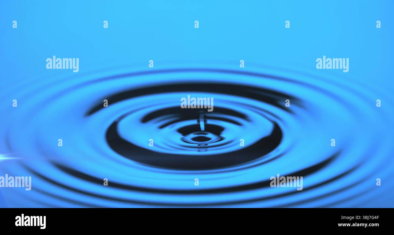 Cattura gocce d'acqua creando increspature concentriche sulla superficie riflettente dell'acqua in studio Foto Stock