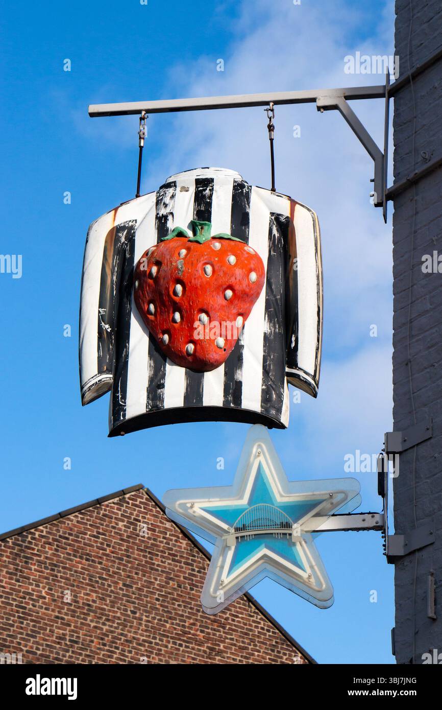 Stravagante cartello da pub con una grande fragola su una maglia a strisce bianca e nera del Newcastle United sotto la stella blu al neon vicino a st james Ground Foto Stock