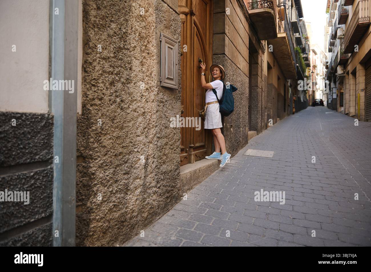 Una donna turistica impegnata nell'esplorazione urbana, godendosi il paesaggio di una strada pittoresca adornata da facciate in pietra, catturando l'essenza del viaggio Foto Stock