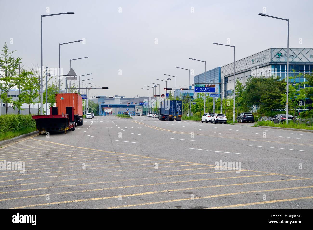Incheon, Corea del Sud - 19 maggio 2025: Un'ampia strada di servizio a sei corsie nel parco industriale appena a est dell'Ara West Sea Lock mostra camion per container, p Foto Stock