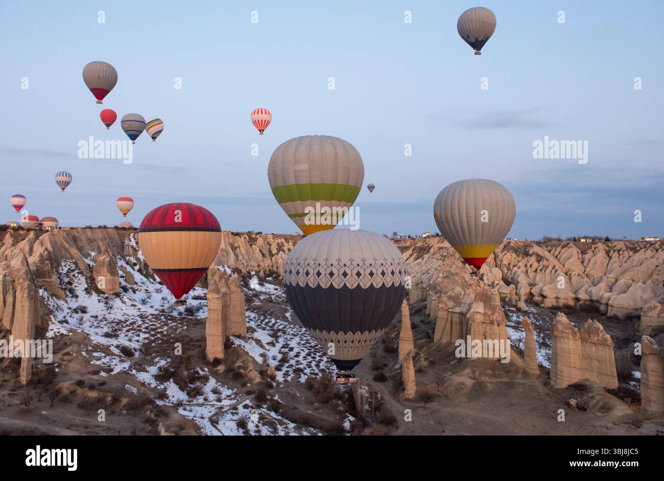 Vista panoramica sulla valle della regione della Cappadocia con camini delle fate e mongolfiere che volano nel cielo Foto Stock