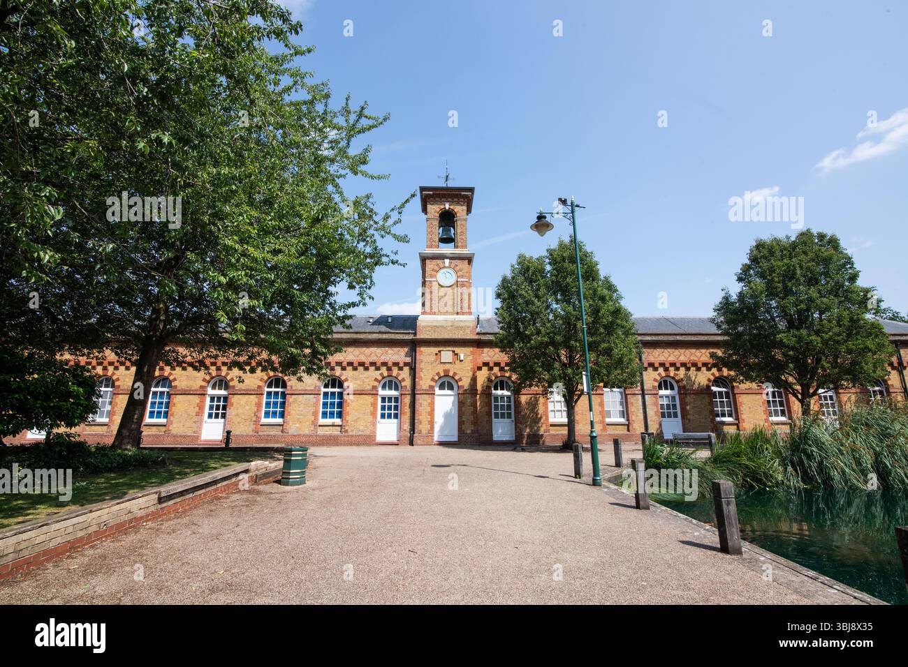 Una vista della torre dell'orologio che si erge in alto accanto al RSA Island Centre nell'Enfield Island Village, che mostra una miscela di storia e moderna spa comunitaria Foto Stock