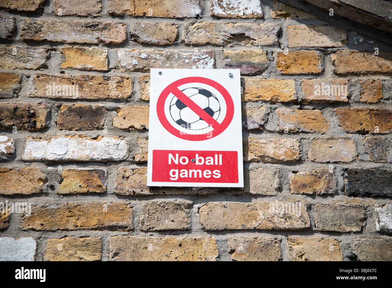 Cartello No Ball Games montato su una parete di mattoni, con un cerchio rosso e una linea sopra il simbolo di una palla, comunemente visto nelle aree residenziali del Regno Unito. Foto Stock